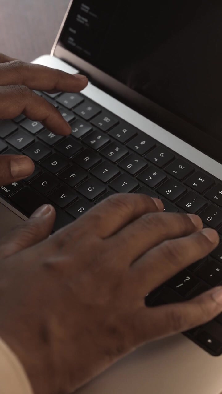 Mani che digitano sulla tastiera del laptop in una stanza calda, accogliente e illuminata