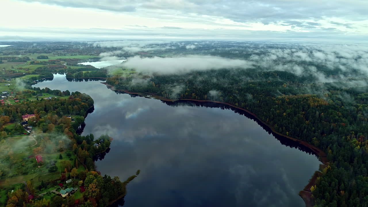Smuk panoramaudsigt over lav tåge, der hænger over skov ved siden af en sø