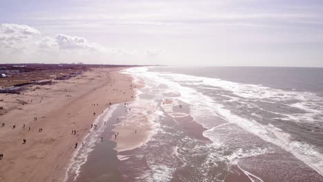 Vista-Aérea-A-Lo-Largo-De-Las-Olas-Del-Mar-A-Lo-Largo-De-La-Costa-De-La-Playa-De-Katwijk-Aan-Zee-En-Holanda-Del-Sur-En-Un-Día-Soleado