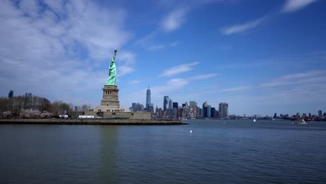 statue of liberty island with nyc skyline in background across water, wide