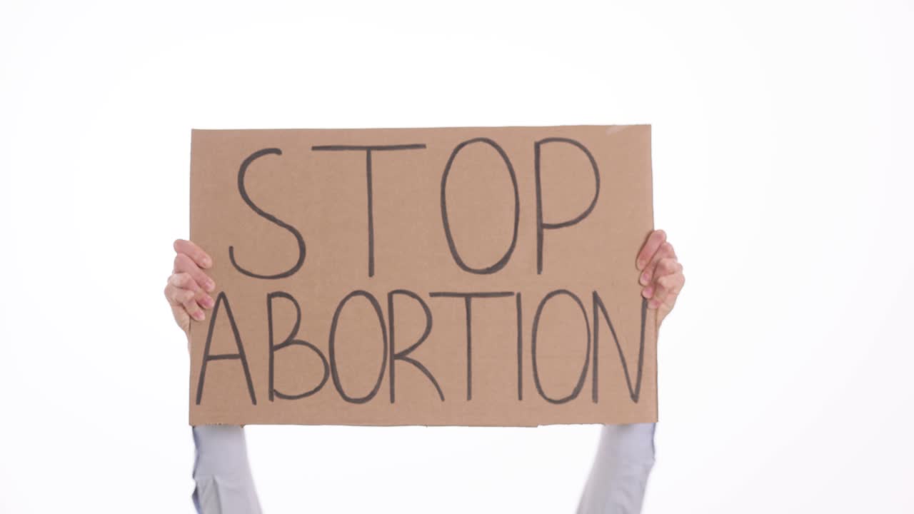 Activist hands hold cardboard sign with words stop abortion