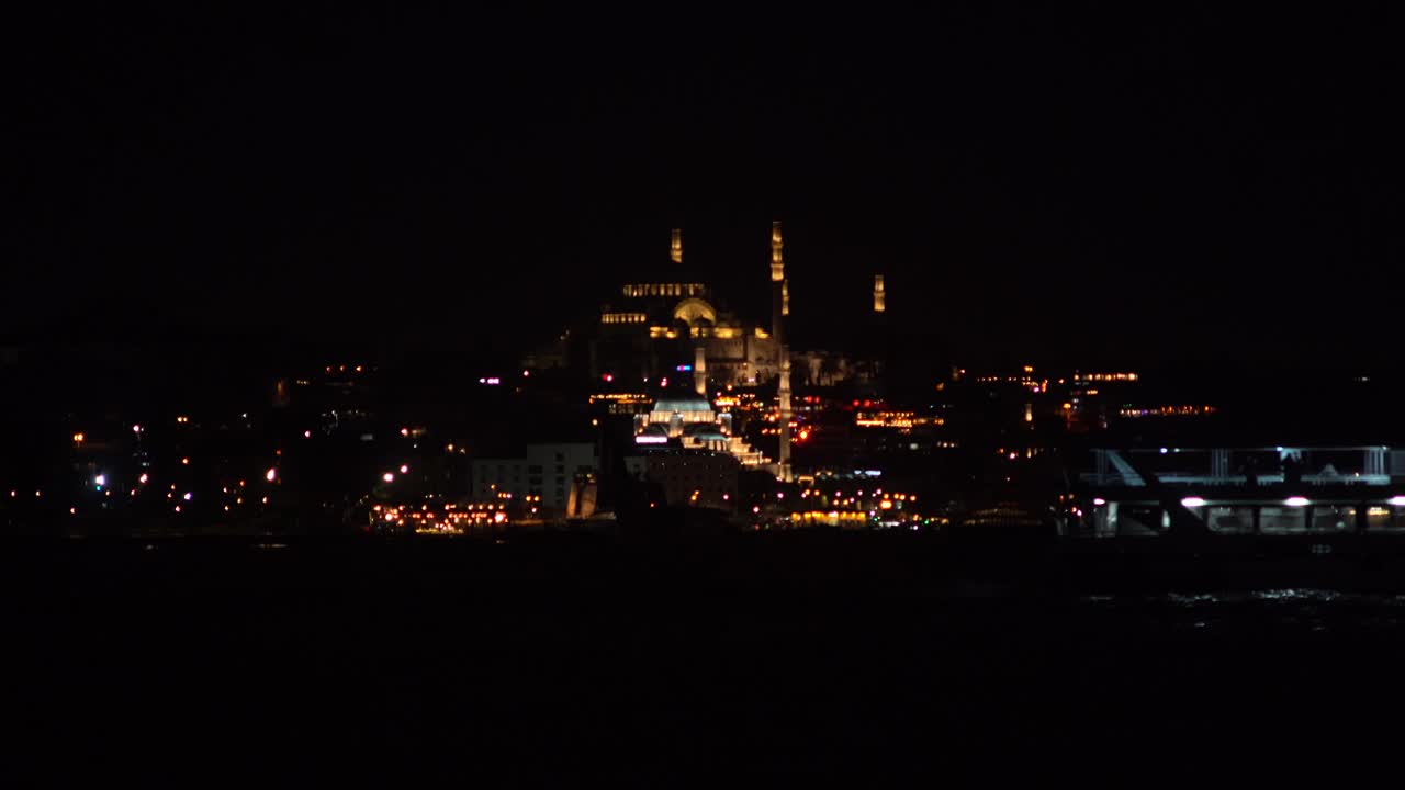 전면에서 페리가 지나가는 술레이마니 모스크의 야간 풍경