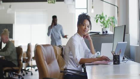 Portrait-of-happy-african-american-businesswoman-with-laptop-in-creative-office