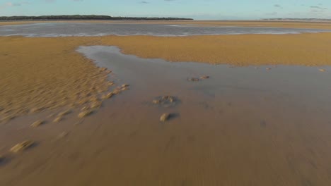 a fast low flying aerial shot of the sand and water at an inlet in victoria australia