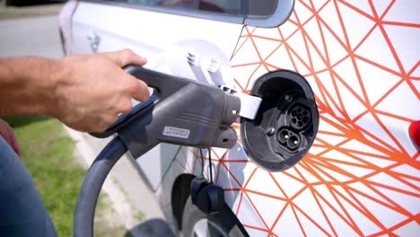 una persona pone un cargador en un coche eléctrico