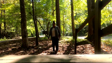 African-American-woman-walking-towards-camera-in-the-woods-holding-bible-and-enjoying-God's-creation