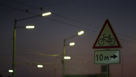 warning red roadsign at night highway closeup. cars headlight beams flashing.