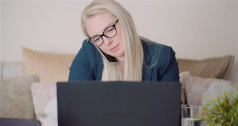 Businesswoman-Working-On-Laptop-On-A-Project-At-Home-Office-While-Talking-On-Mobile-With-Client-2