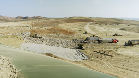 panoramic view of a large landfill with heavy machinery and waste