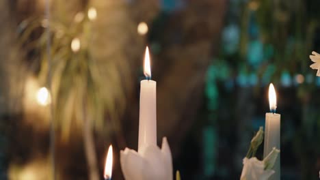 flames of white candles flickering in warm dreamy garden setting during evening