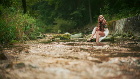 beautiful woman touching water during meditation and relaxation by the river