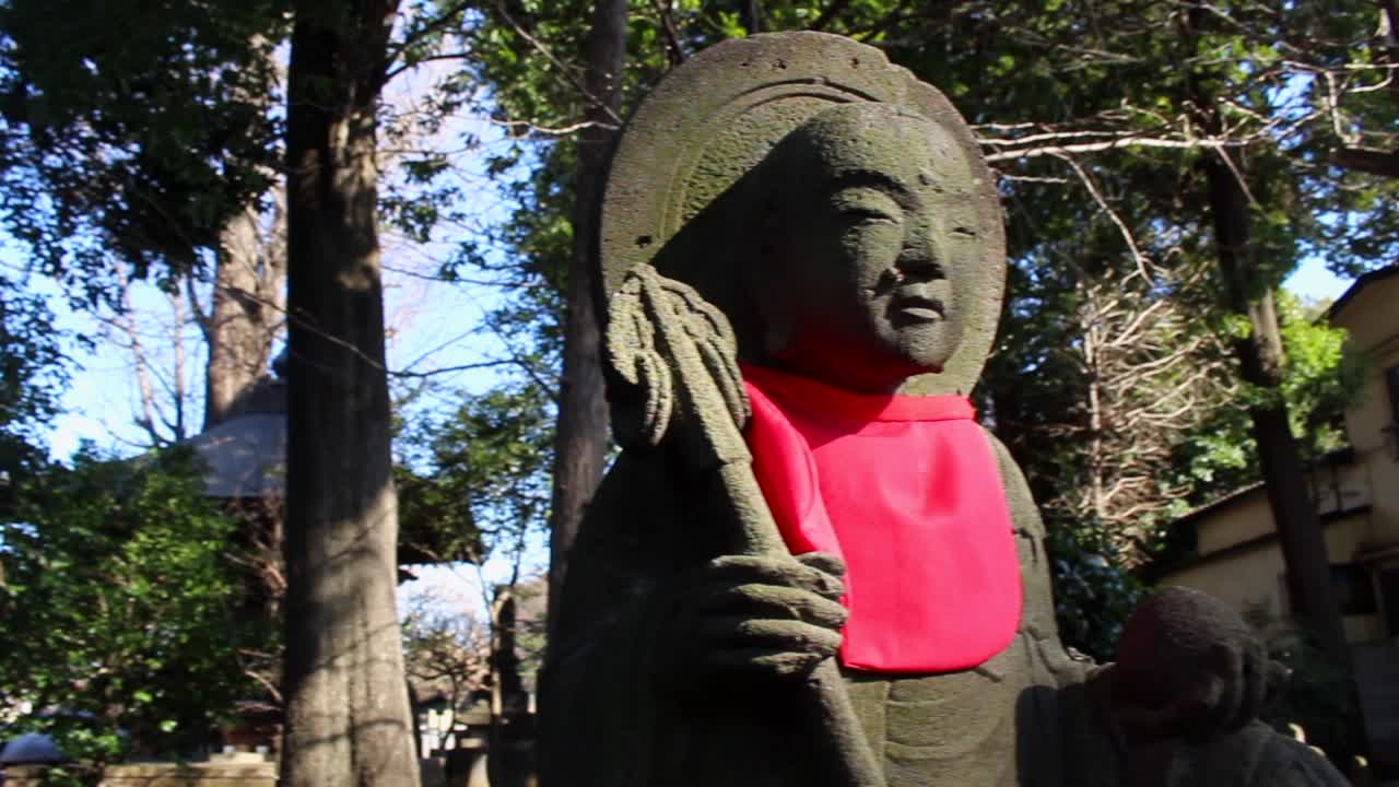 One of the many Buddhas in a temple in Tokyo. It is very common to see them with a red bib and with different outfits that the local people put on according to the seasons of the year