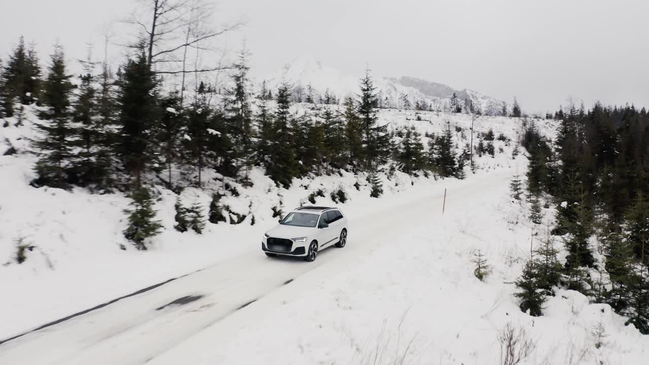 vista aérea de un automóvil conduciendo por una carretera cubierta de nieve en eslovaquia durante el invierno