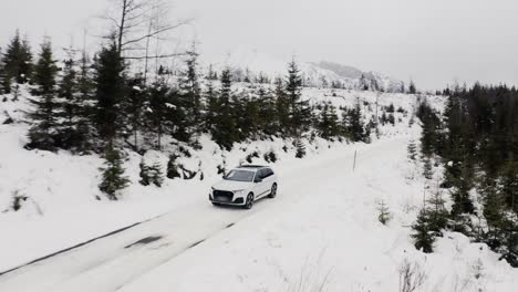 aerial view of a car driving along snow-covered road in slovakia during winter