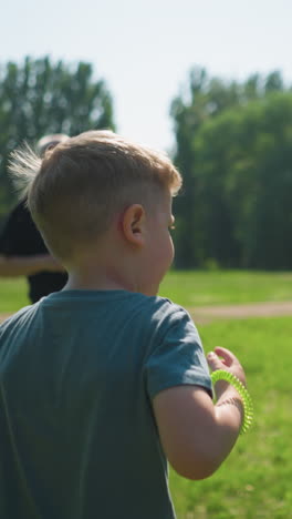 primer plano de una familia haciendo ejercicio al aire libre en un campo cubierto de hierba, con un niño pequeño, un niño adolescente y su abuelo saltando, con un poste de gol borroso visible detrás
