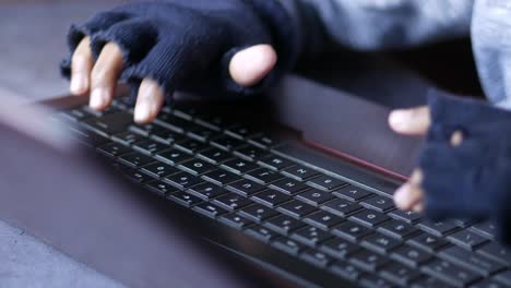 person typing on a laptop with gloves