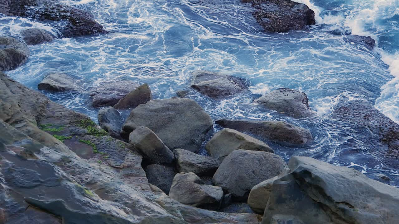 Onde che si infrangono tra grandi rocce su una scogliera costiera durante l'estate.