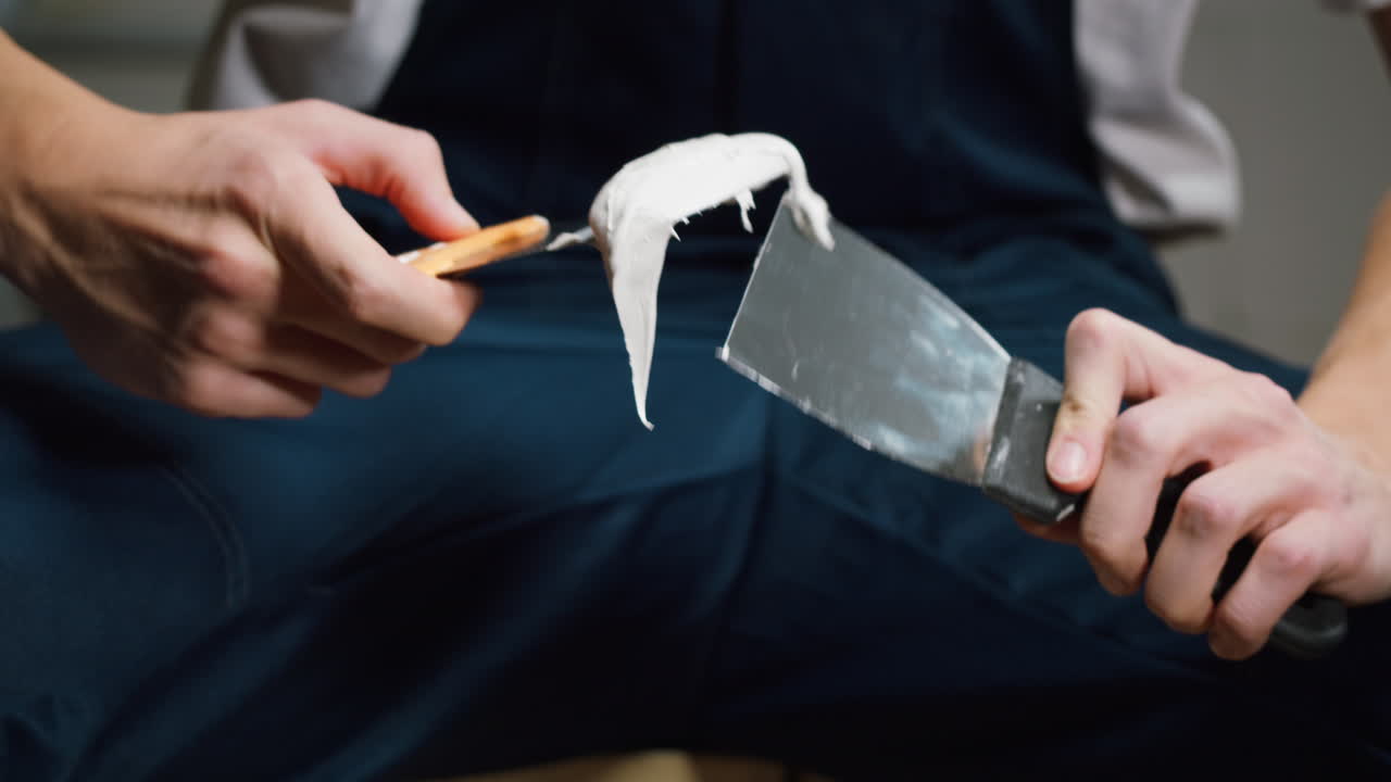 Close-Up of Worker Mixing Putty with Spatulas