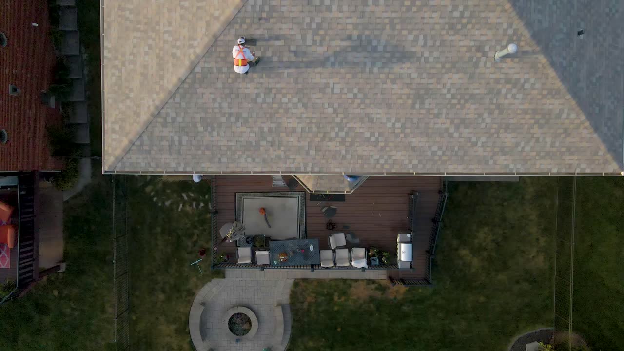 Aerial view of construction workers laboring in a backyard patio with outdoor furniture, a fire pit, and a well-maintained lawn, showcasing a cozy and inviting outdoor living space.