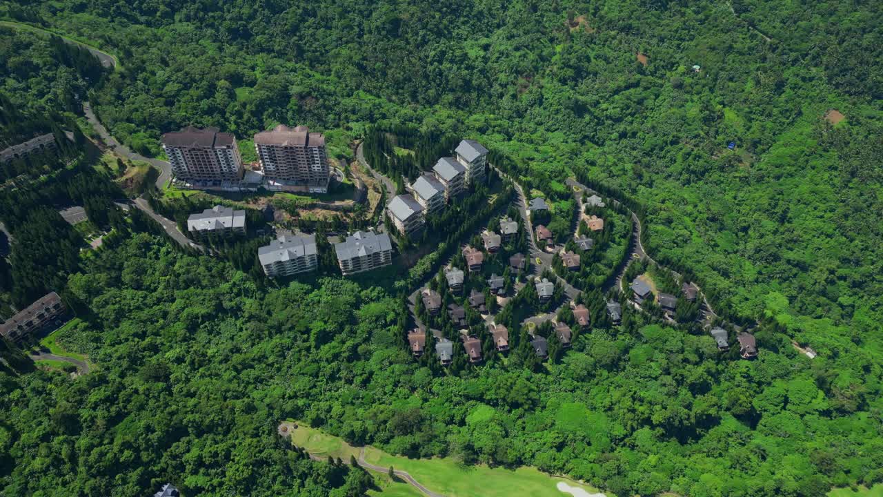 A higher rotating aerial of a Woodlands villa in Tagaytay Highlands surrounded by pine trees and hillside terrain in Batangas, Philippines