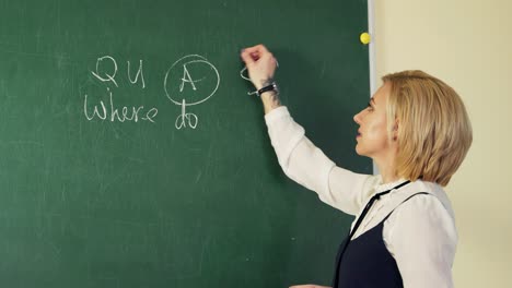 in an english class, a teacher writes with chalk on a blackboard and teaches students a lesson
