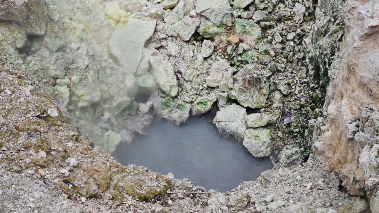 exploración del vapor ascendente de una pequeña piscina de agua rodeada de rocas volcánicas - wai-o-tapu,nueva zelanda