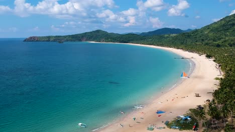 Aerial-reveal-shot-of-palm-trees-and-people-on-Nacpan-beach,-El-Nido-,-Palawan,-Philippines