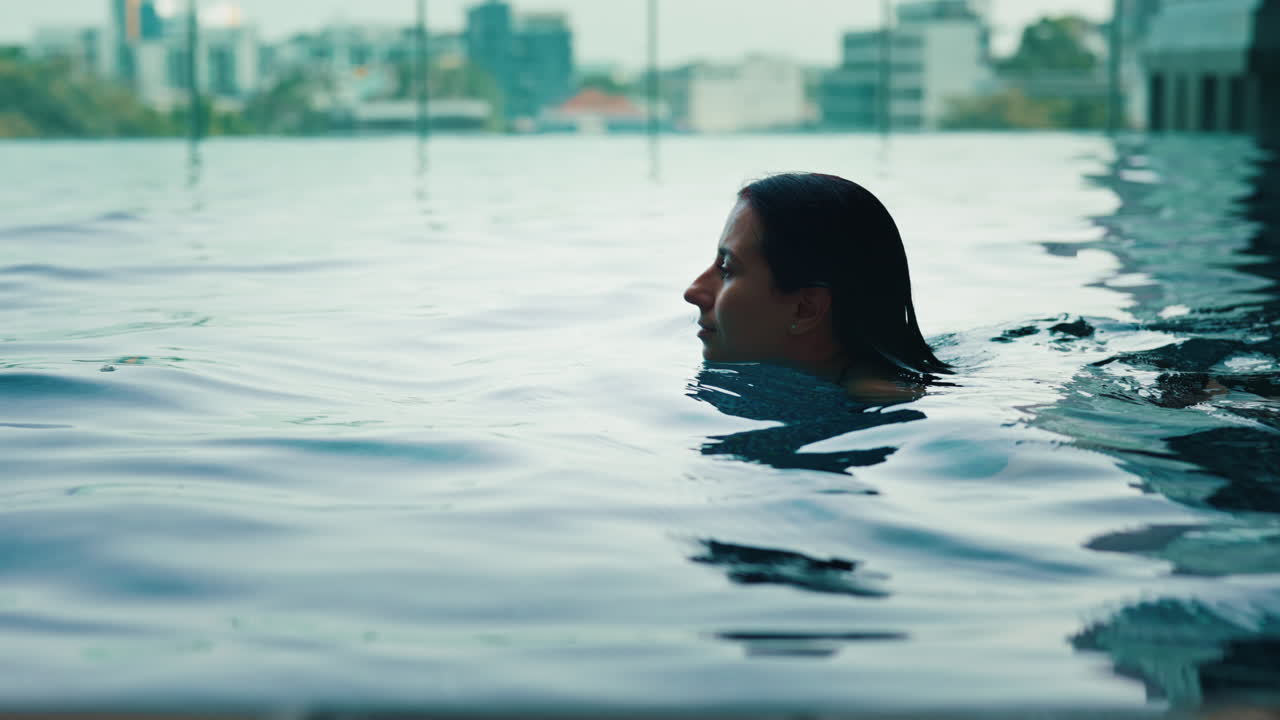 Woman Swimming in a Rooftop Pool with City View