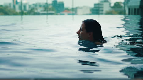 woman swimming in a rooftop pool with city view