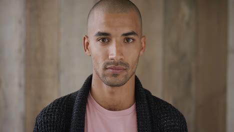 portrait of mixed race man looking serious independent student handsome bald male wooden background slow motion