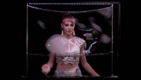 girl does tricks with soap bubbles. she plays with large bubbles, using her fingers tremor, connects them