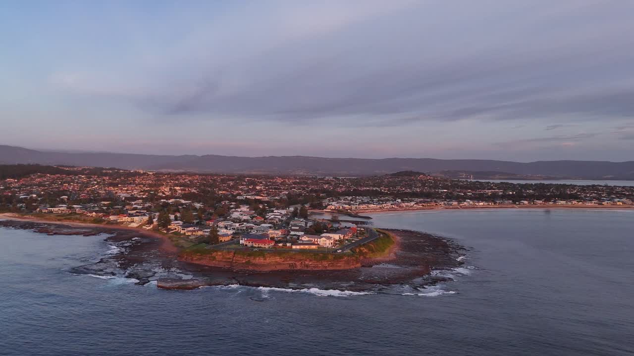 Aerial orbit above Barrack Point, Australia, featuring coastline and seaside town buildings with calm ocean waters