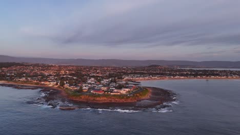 aerial orbit above barrack point, australia, featuring coastline and seaside town buildings with calm ocean waters