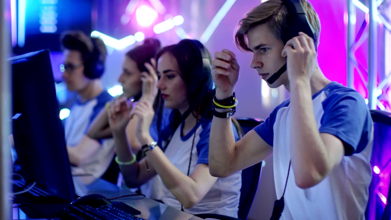 Team of Teenage Gamers Get Ready for eSport Tournament, Put on Their Headsets. Tournament Area/ Internet Cafe Looks Cool with Neon Lights.