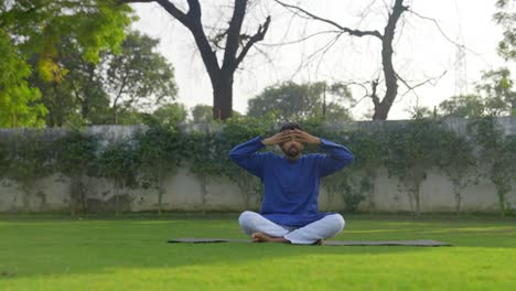 Young-Indian-man-doing-breathing-exercise-in-a-park