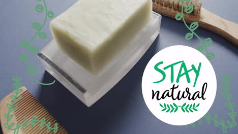 animation of stay natural text and leaves over organic soap, wooden comb and brush