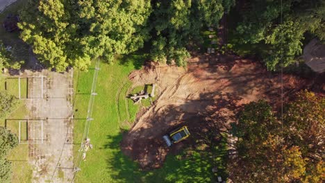 aerial view of construction zone with heavy machinery in residential green space