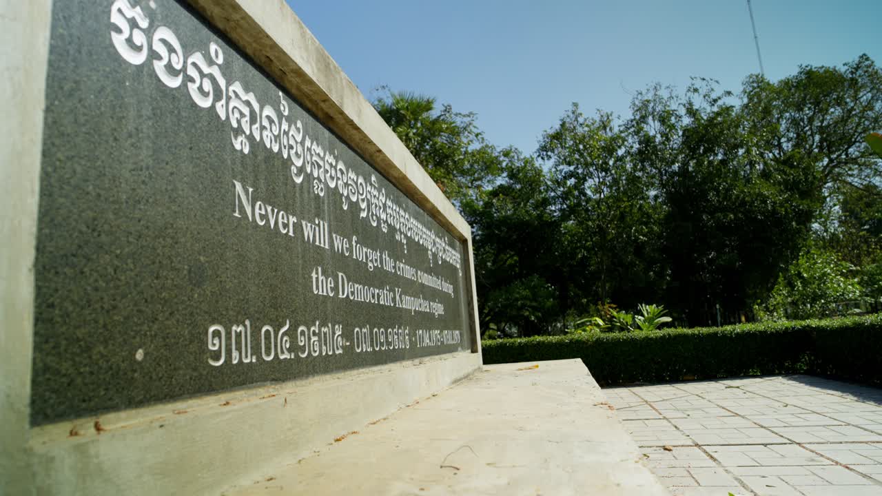 Stone monument remembering Khmer Rouge atrocities stands quiet, Cambodian garden