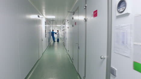 Two-scientists-speaking-in-laboratory-corridor.-Science-man-and-woman-talking