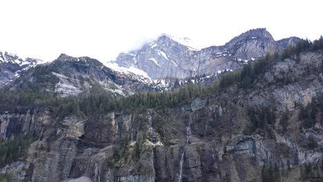 drone flight over a beautiful alpine valley, waterfalls and high snow capped mountains