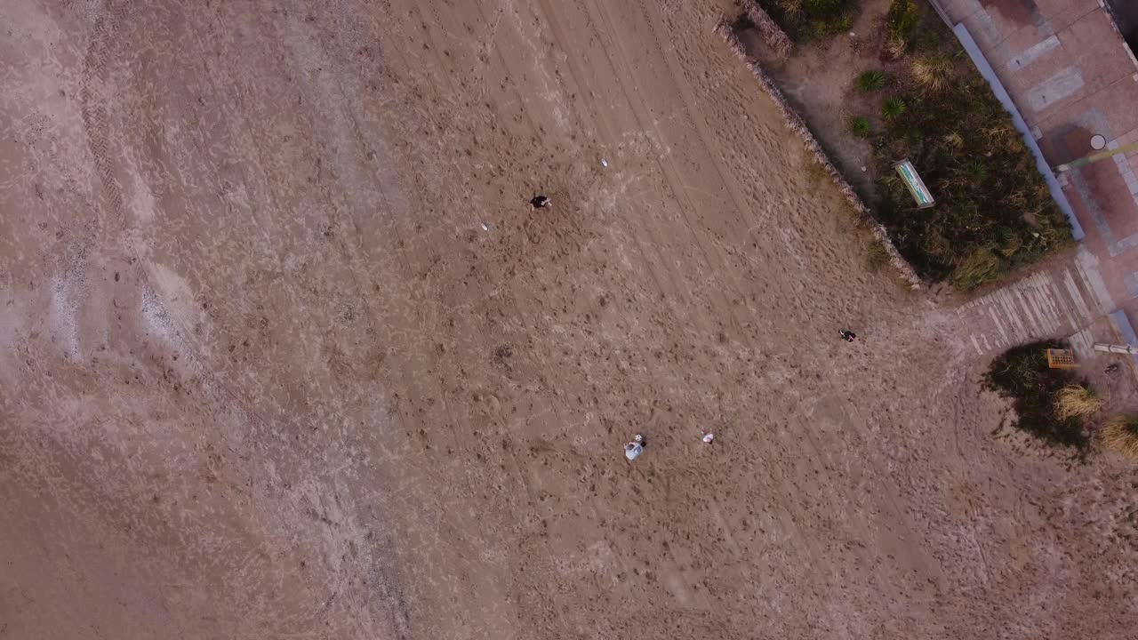 дети играют в футбол на пляже с высоты птичьего полета