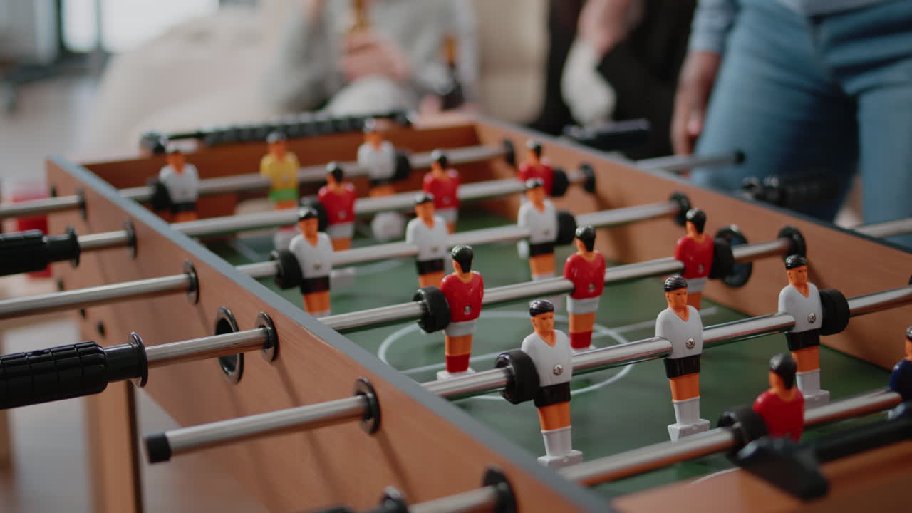 Close up of colleagues playing at foosball table after work