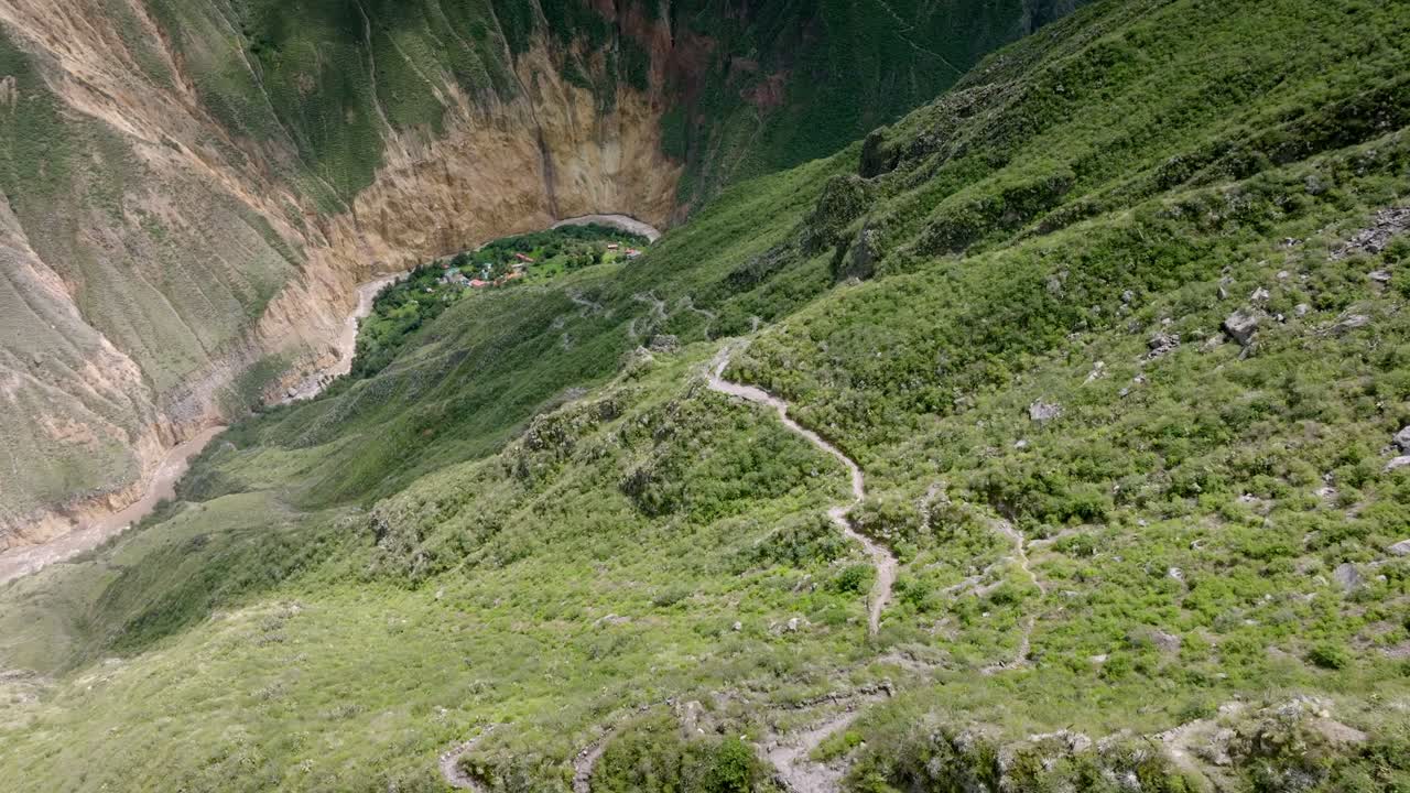 Drone shot captured midway along the path from Cabanaconde to Sangalle, showcasing the dramatic descent with the Colca Canyon's vast landscape and the Oasis of Sangalle in the distance.