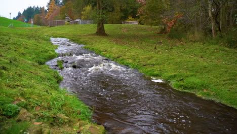 river flowing through the green fields in the countryside during autumn - drone shot