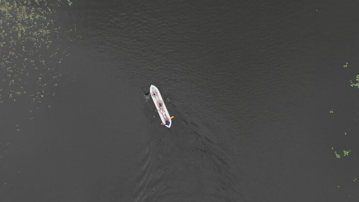 Aerial drone tracking top-view shot of a dinghy boat sailing in a lake