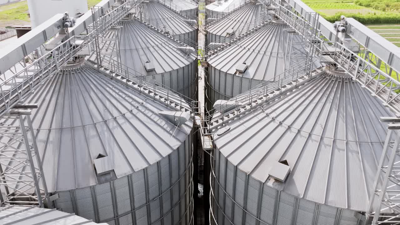 Smooth low drone flight moves forward above shiny silver grain silos in Latvia