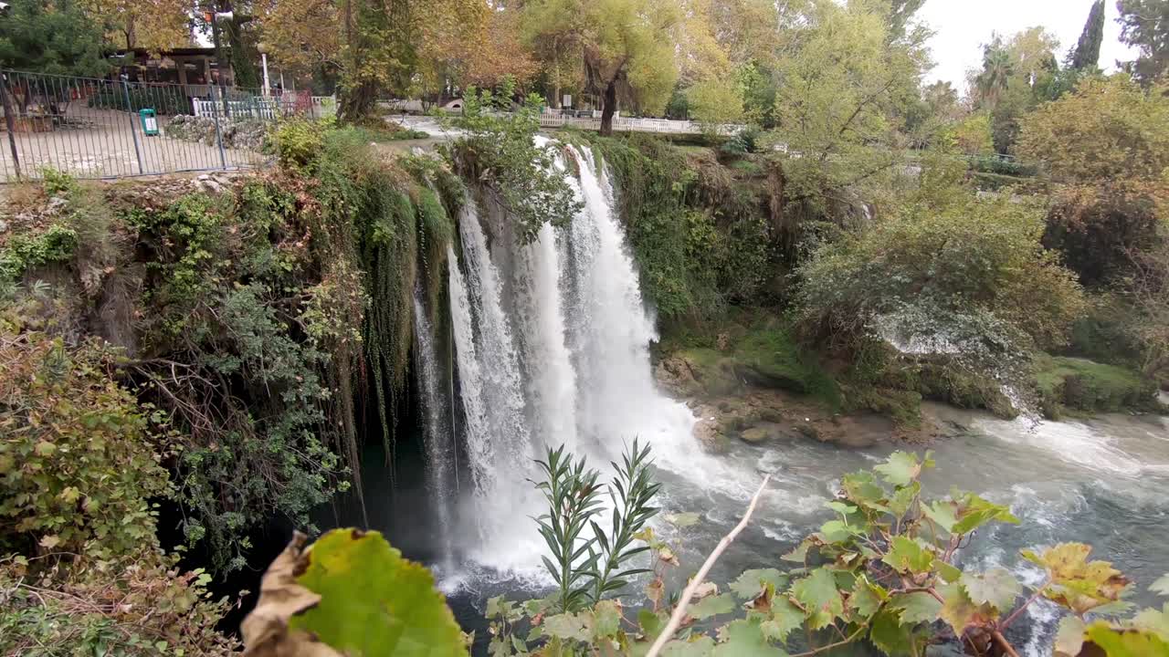 Ripresa della cascata di Duden ad Antalya, Turchia, da dietro foglie e piante