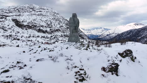 eagle sculpture of stone at the simplon pass with in the background the high swiss alps covered by snow