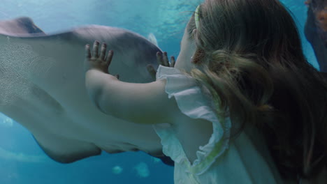 niña feliz con su madre en el acuario mirando rayas nadando con peces en el tanque niño observando animales marinos con curiosidad divirtiéndose aprendiendo sobre la vida marina con su madre en el oceanario