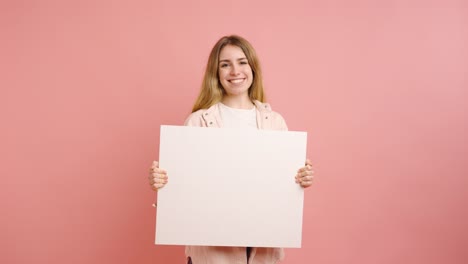 young woman holding blank white sign on pink background